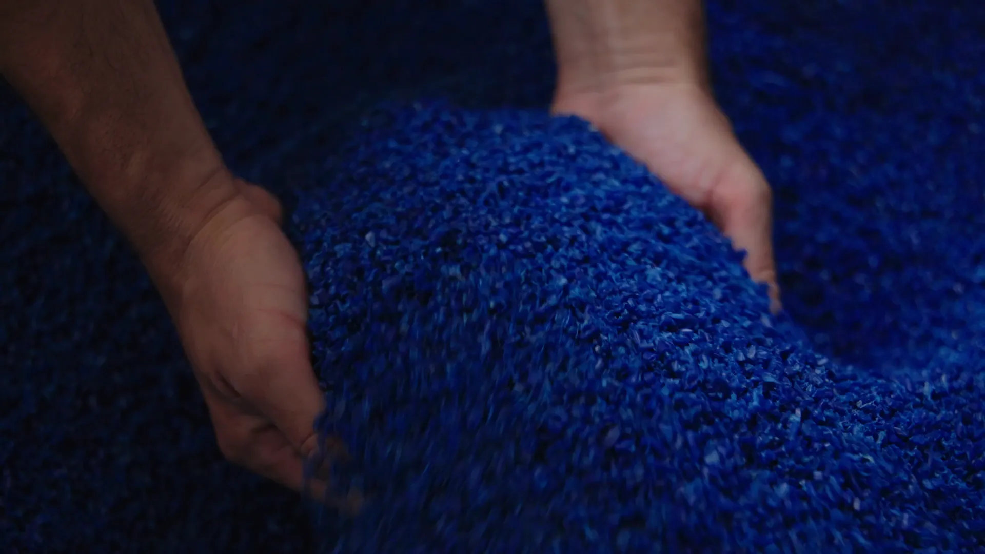 Hände mit blauem Kunststoffgranulat